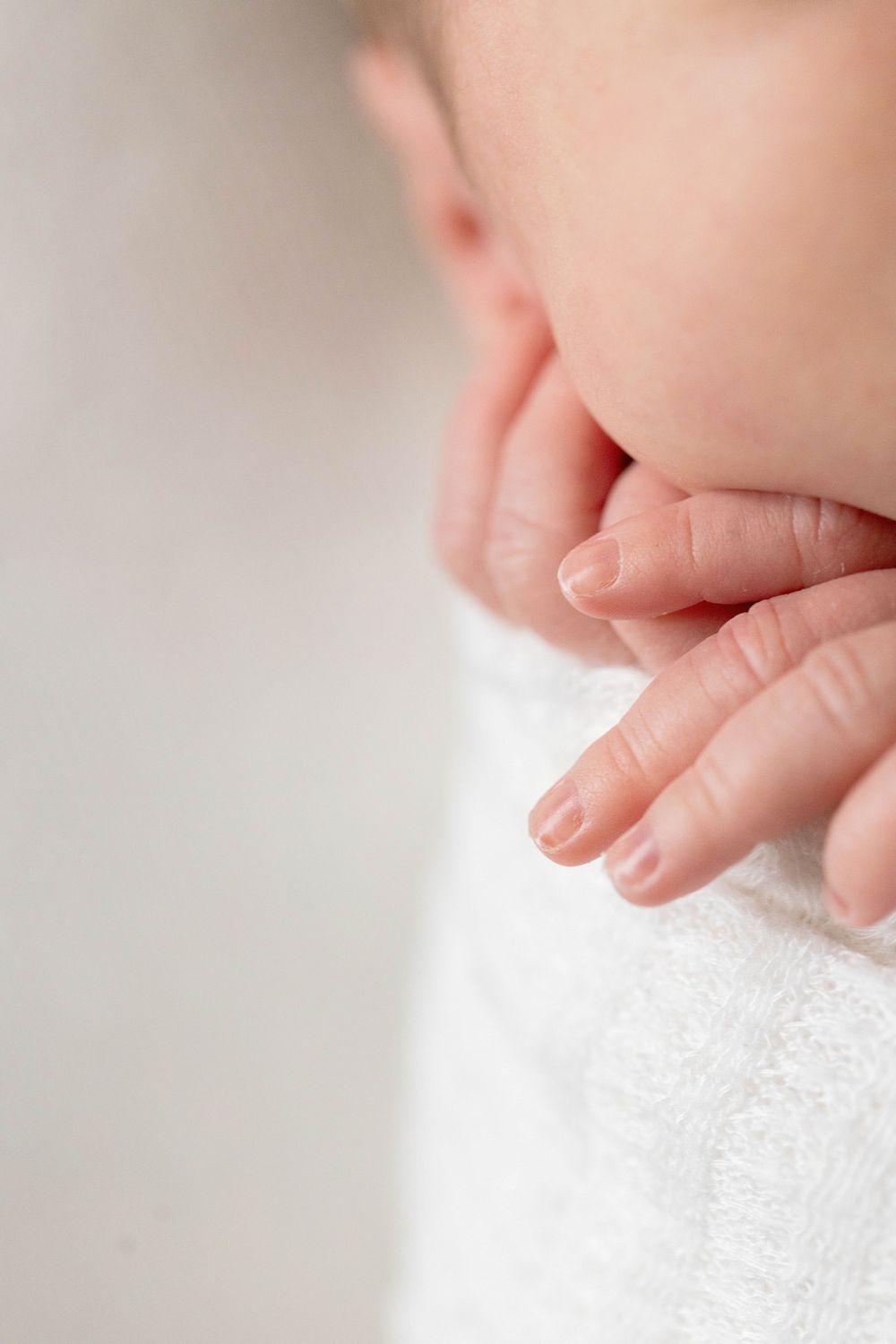 Close-up of tiny newborn baby fingers against white fabric during a lifestyle newborn session in Springfield, MO.