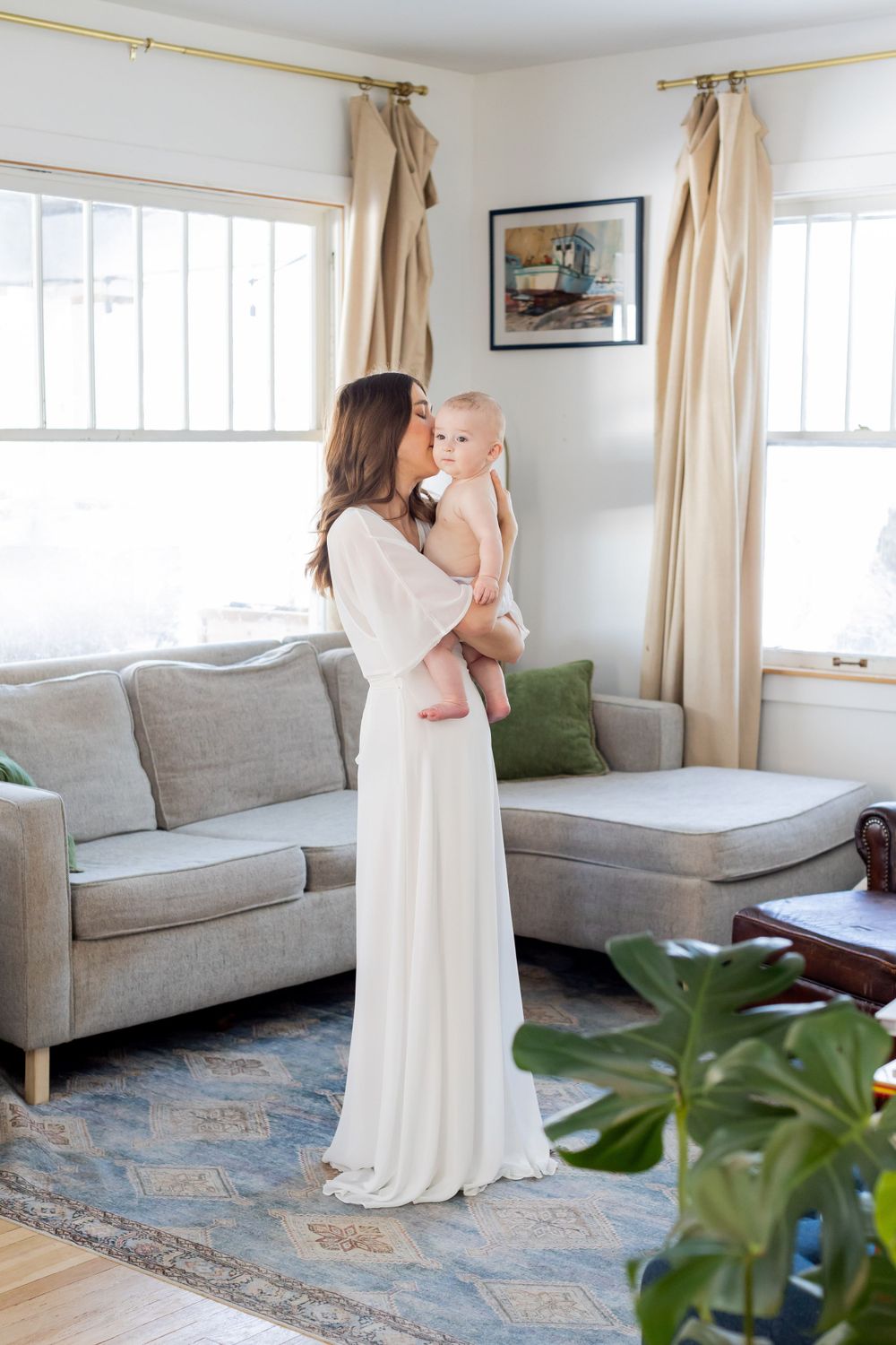 Elegant living room with mother is a white dress holding baby boy taken during a lifestyle session in Springfield, MO.