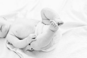 Black and white close-up of tiny baby feet resting on soft white fabric taken in a lifestyle session in Springfield, MO.