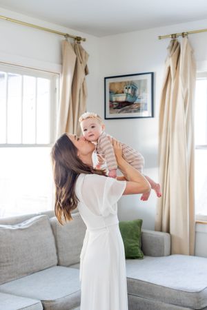 A tender moment of a mother in a white dress kissing baby on the cheek during a lifestyle session in Springfield, MO.