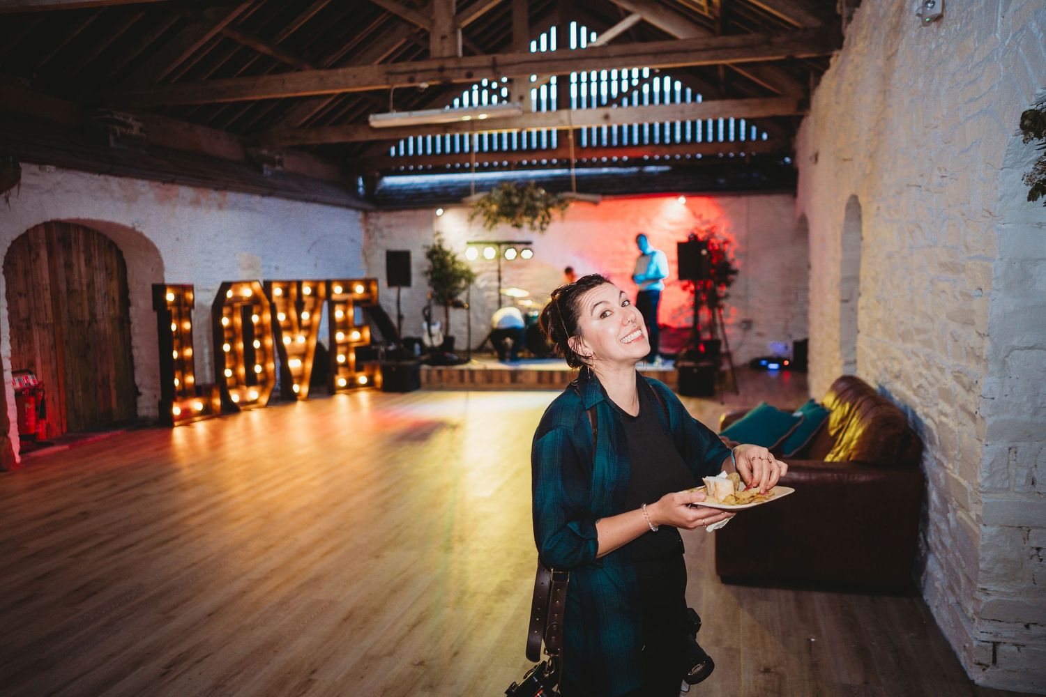 Wedding reception venue with illuminated LOVE sign and rustic stone walls.