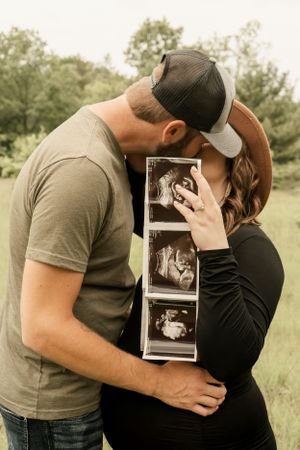 Couple looking at ultrasound photos together in an outdoor setting.