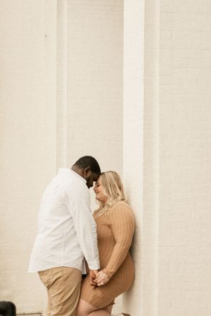 Intimate moment captured against a white wall in soft, neutral tones.
