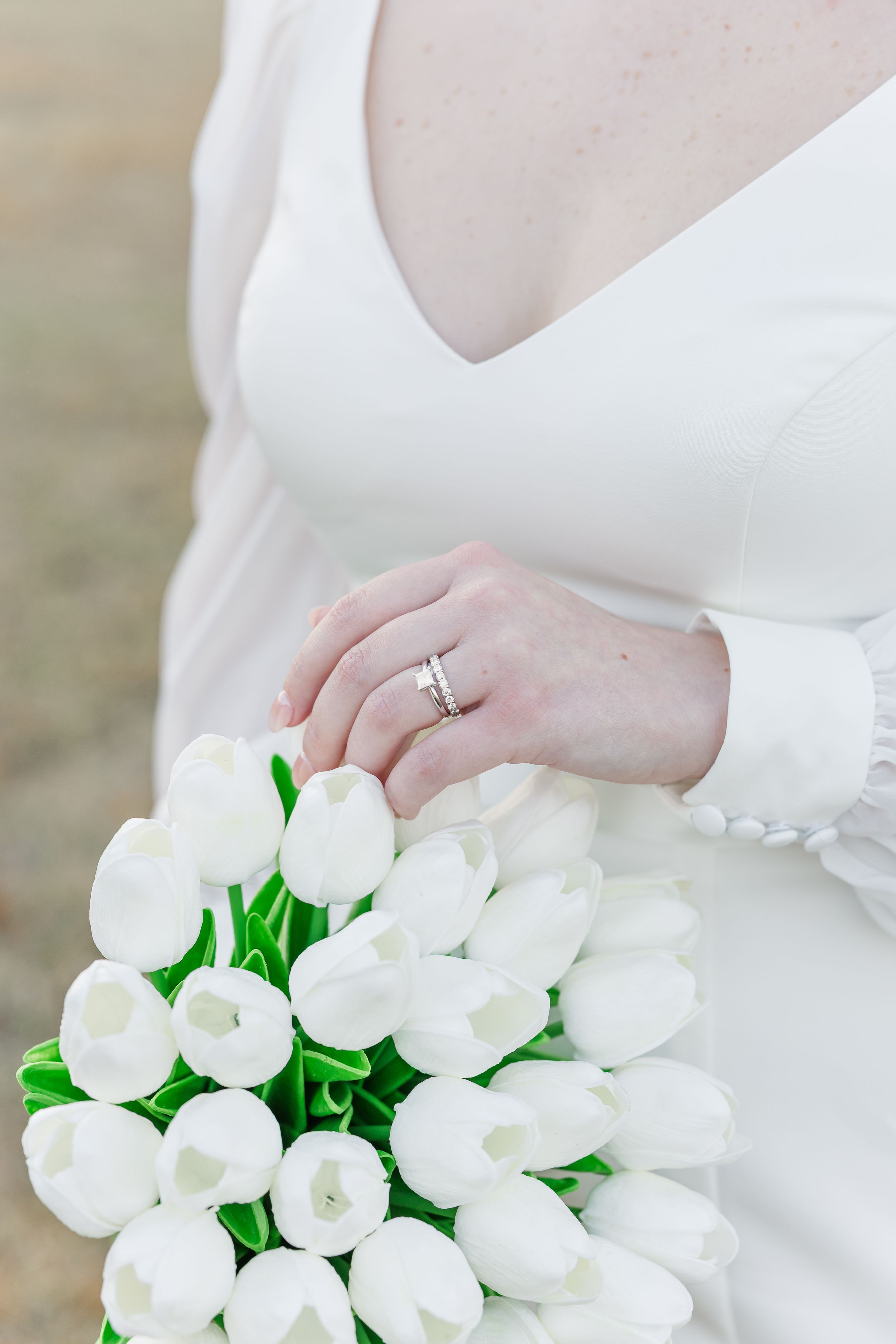 Close-up shots of a white tulip bridal bouquet with an engagement ring detail against a white wedding dress.