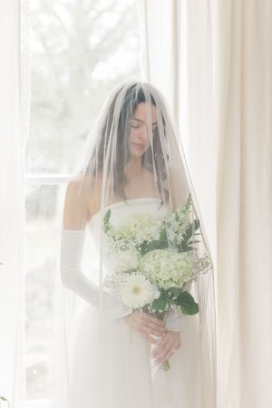 A series of soft, ethereal bridal portraits with white flowers and a flowing veil in natural window light.