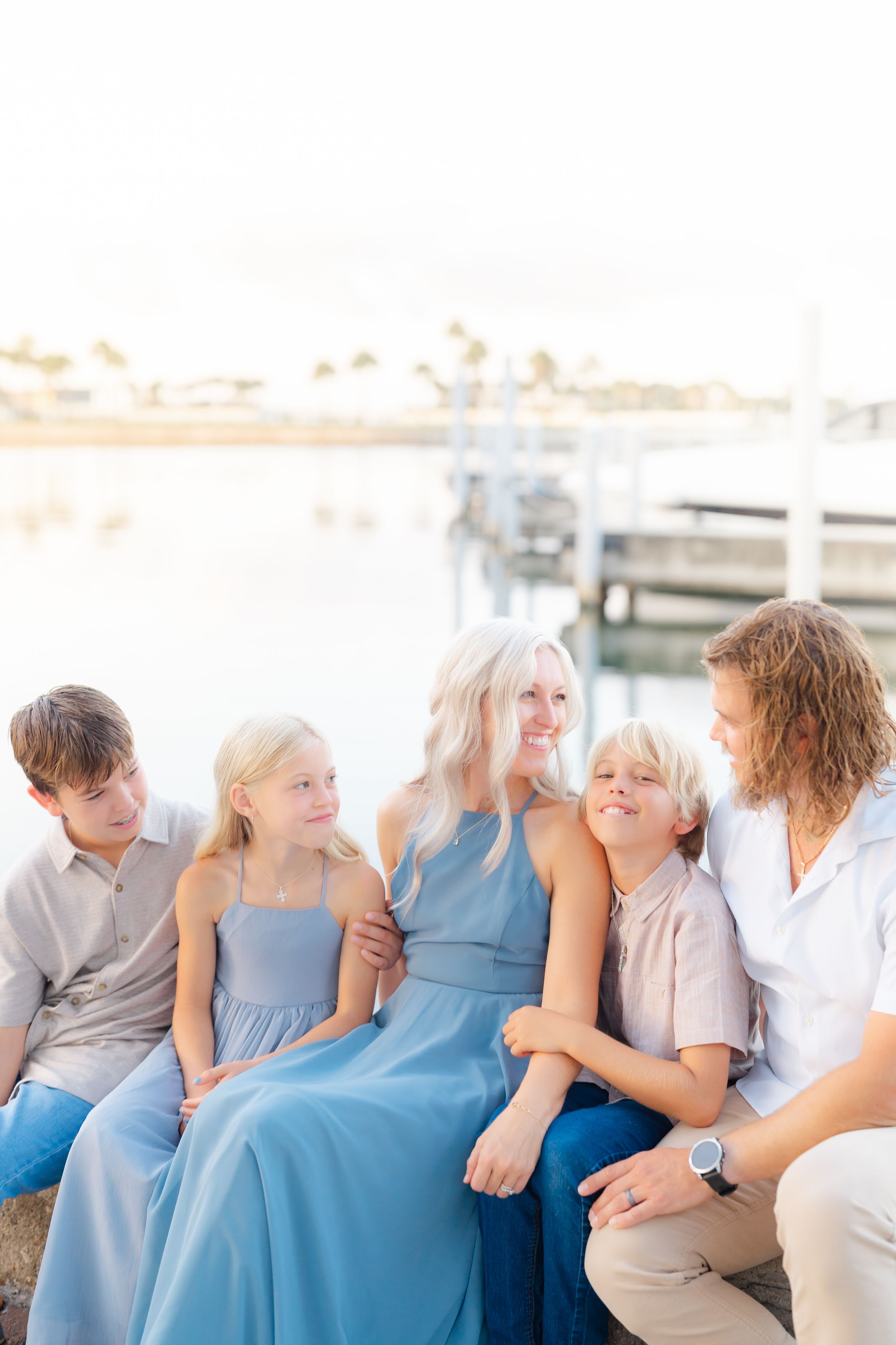 family sitting on the seawall, having fun, during their family session in downtown St. Petersburg, Vinoy Park