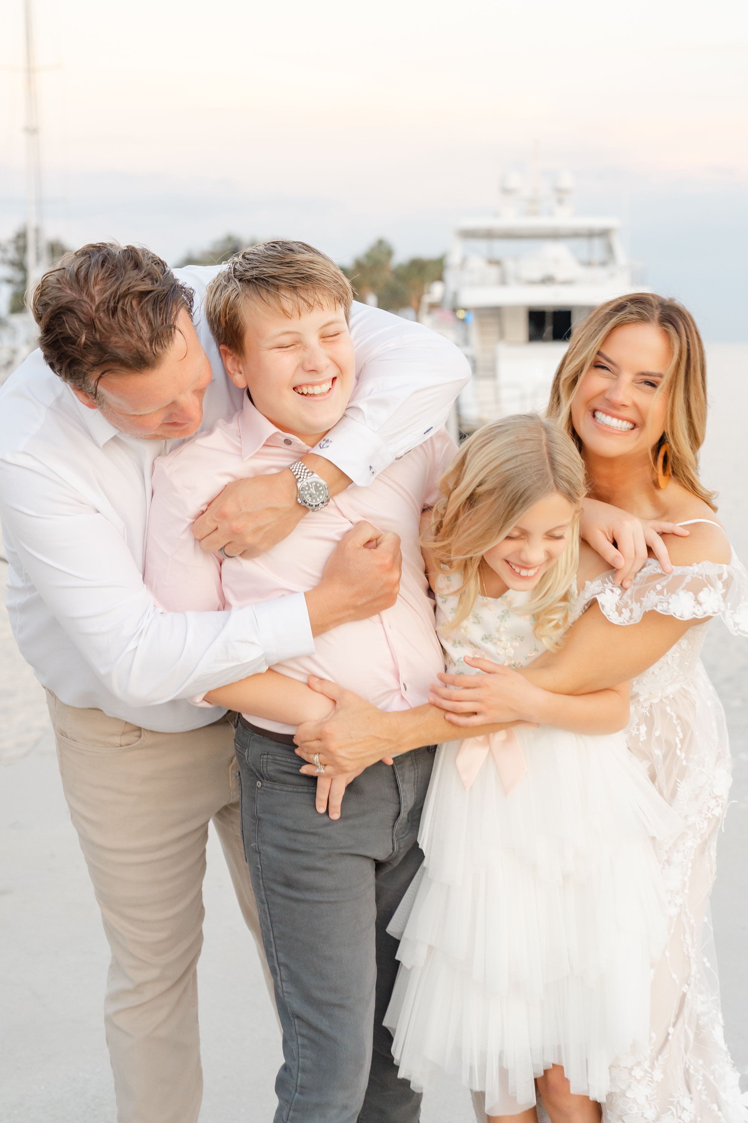 family embracing each other on the docks of The Vinoy overlooking the water and St. Pete Pier during their family photoshoot in St. Pete FL