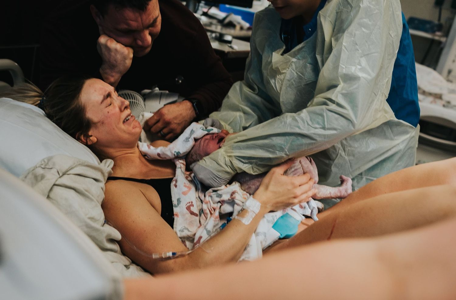 Medical team assisting during intense childbirth moment in hospital room.