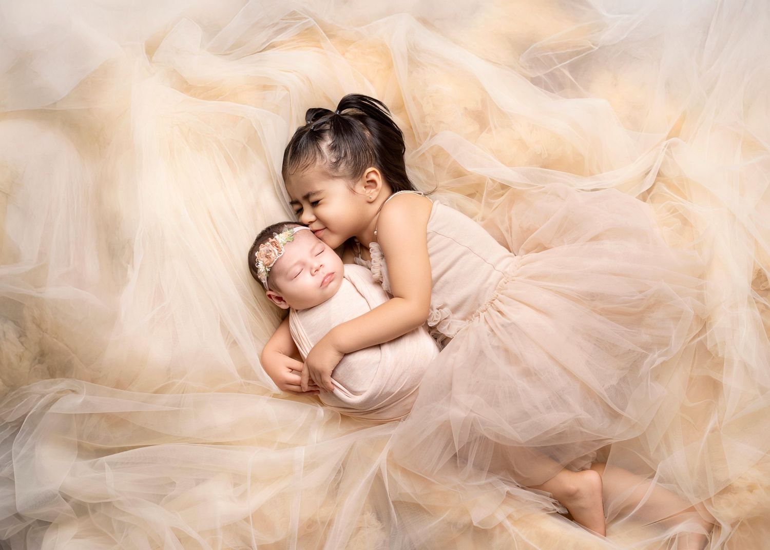 Newborn photography Covina CA sibling kissing baby girl in soft neutral studio setup