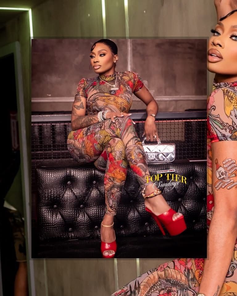 Heavily tattooed woman in floral jumpsuit and red heels posing at Top Tier Sundays event.