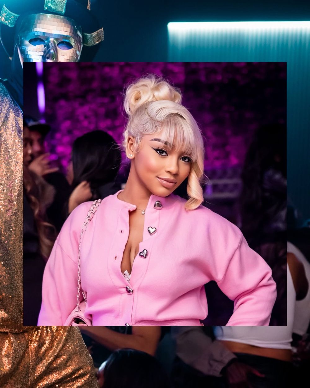 Young woman with blonde updo wearing pink zip-up jacket with heart buttons at a vibrant nightclub event.