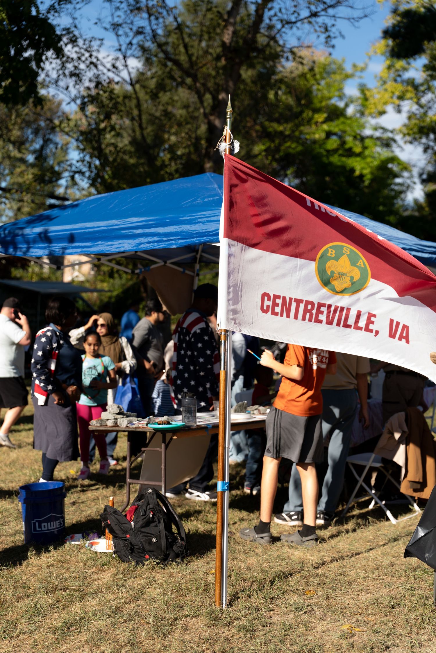 Outdoor event with state flags and tents set up on grassy field during daytime.