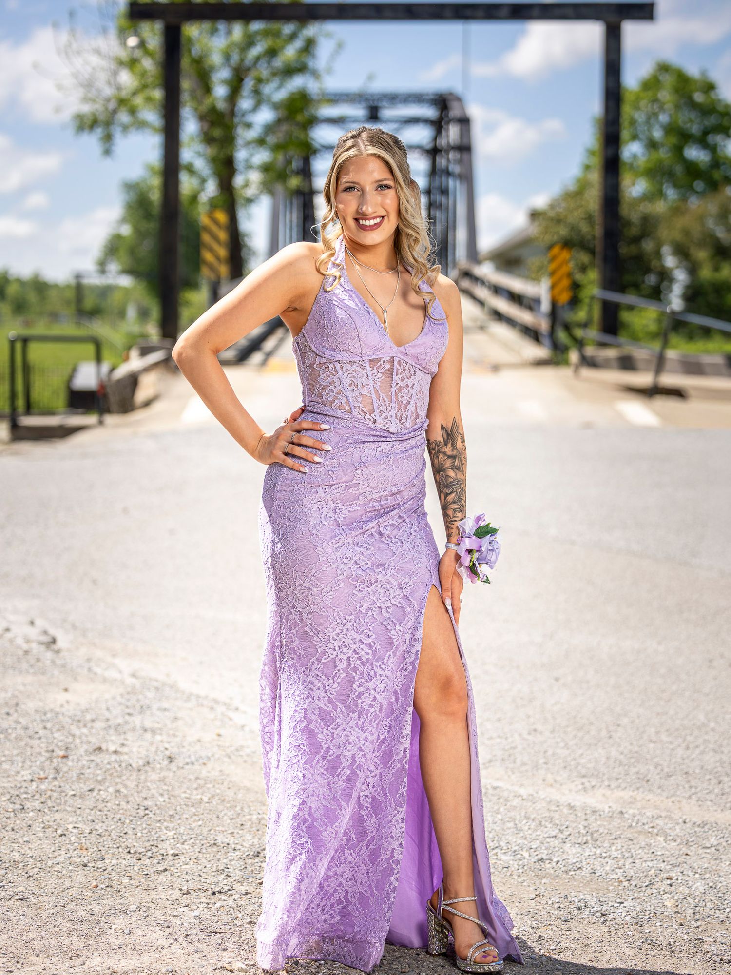 Young woman in lavender lace prom gown with slit poses on War Eagle bridge. Photo taken by Trevel Young Photography