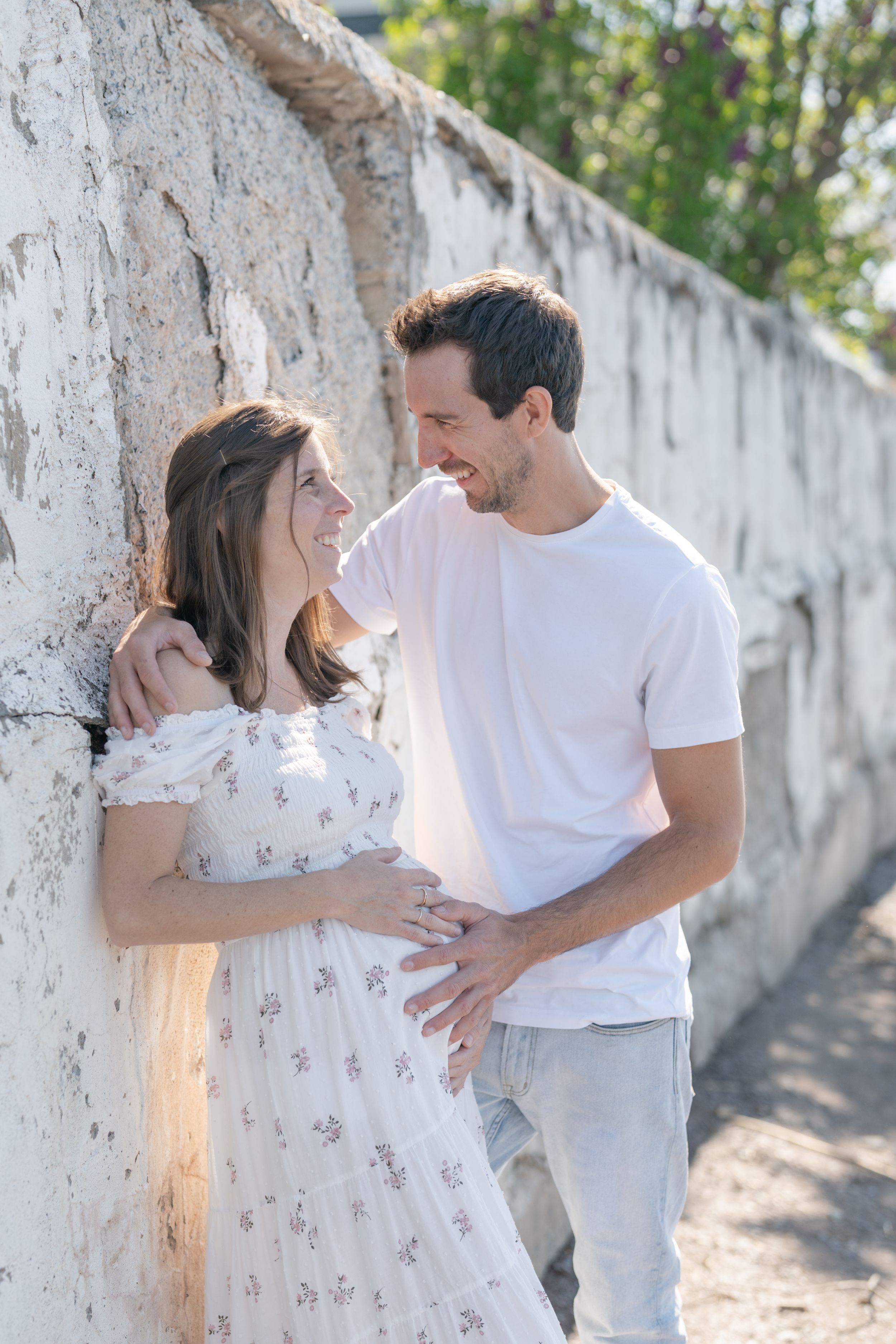 Futurs parents sur la plage à la marina de Cap-Rouge partageant un doux moment adossés à un mur de béton blanc