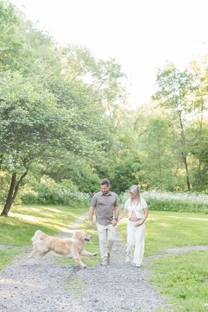 Couple de futurs parents et leur chien marchant sur les sentiers boisés du Parc des Hauts-Fonds à St-Augustin lors de leur séance maternité