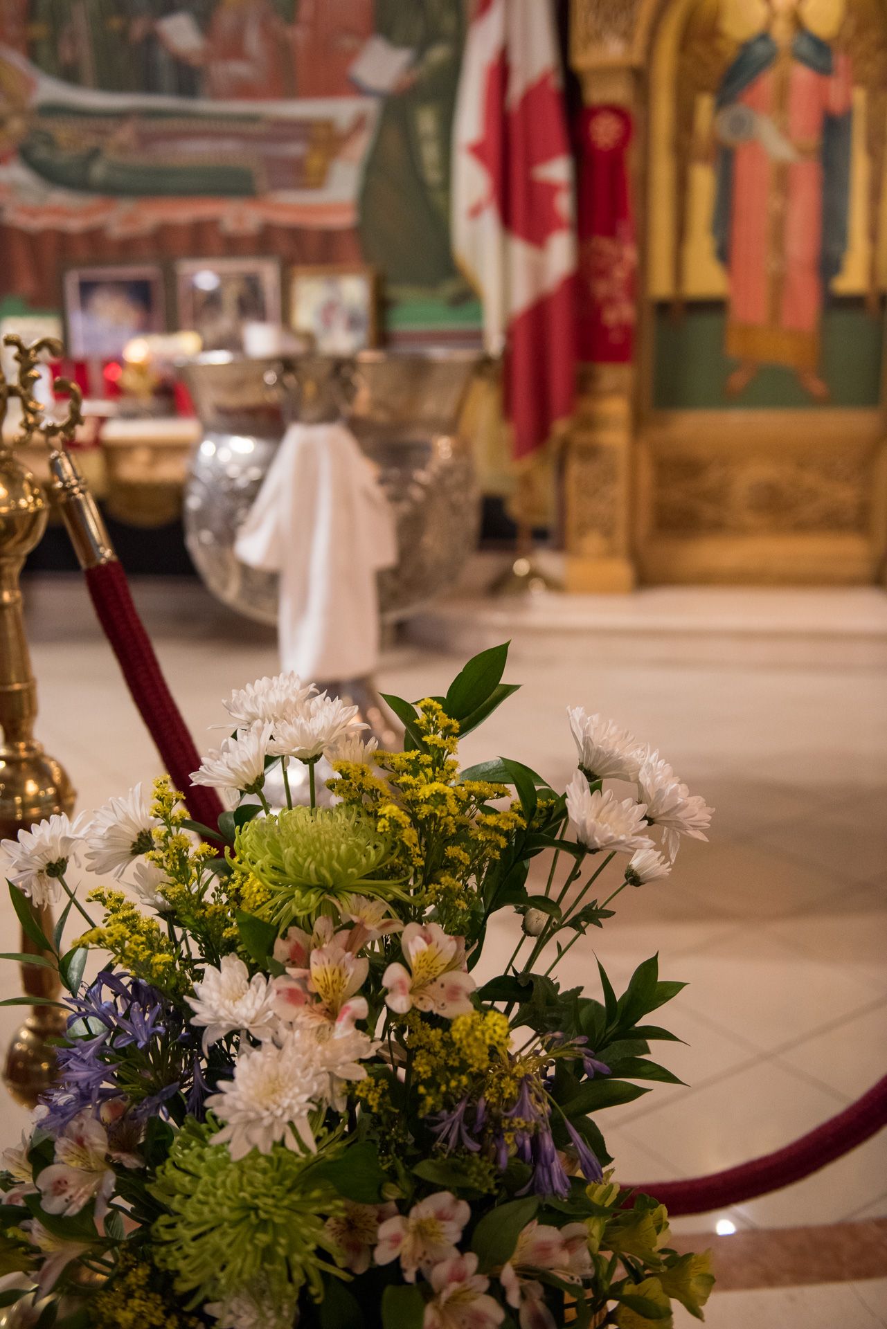 Elegant floral arrangement with white and green flowers decorating Orthodox church interior with Canadian flag.