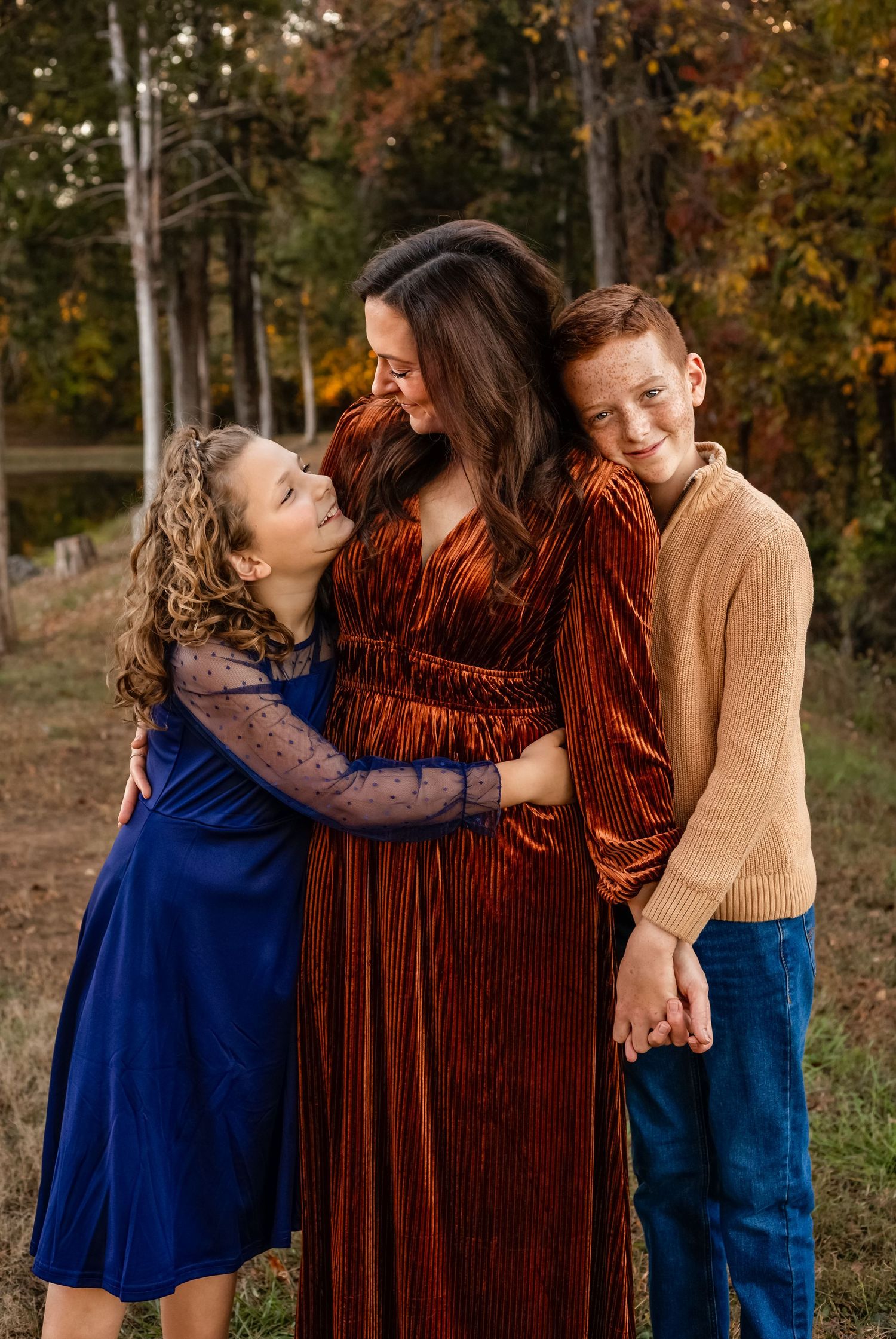 A mother hugs and smiles with her children against a colorful fall backdrop, by Charlottesville family, baby, and maternity photographer.