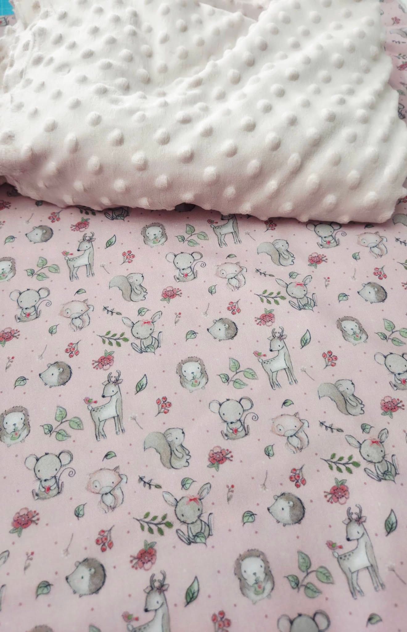 Pink baby blanket with woodland animals print paired with white dimple minky fabric.