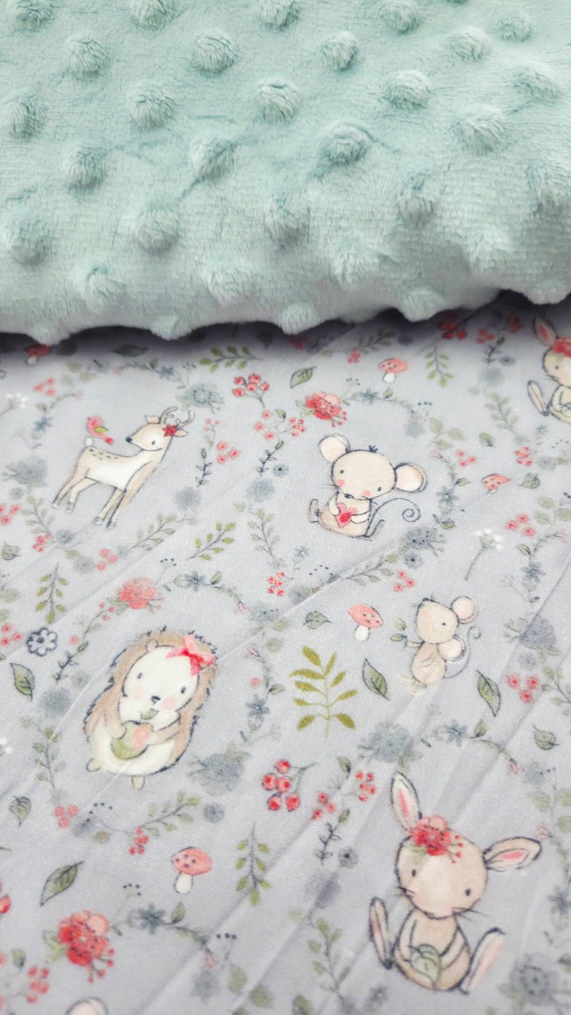 Soft baby blanket with mint green minky dot fabric and woodland animals print featuring deer, mice, hedgehog, and bunny.