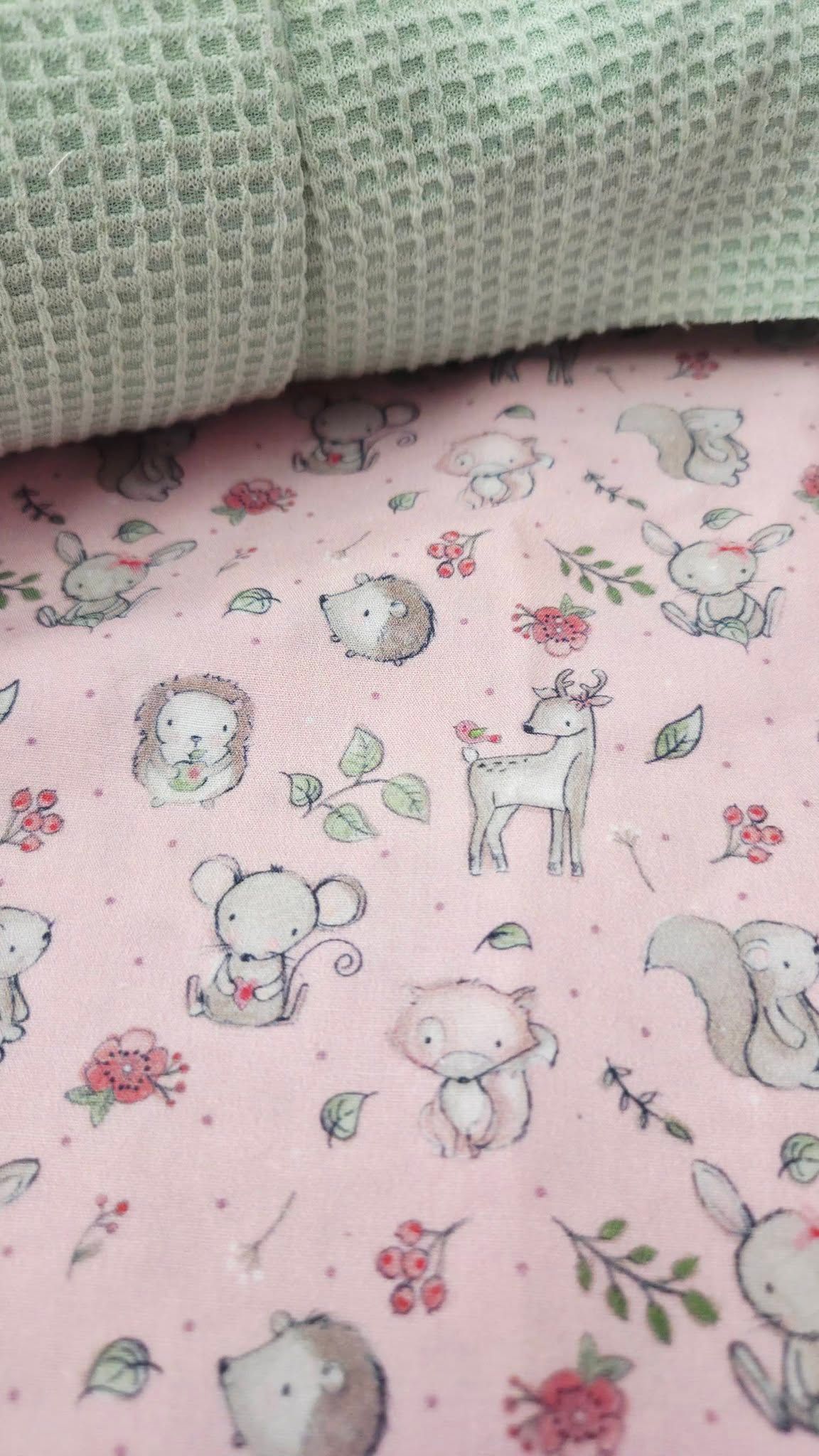 Close-up of pink woodland animals cotton fabric paired with mint green waffle knit textile.