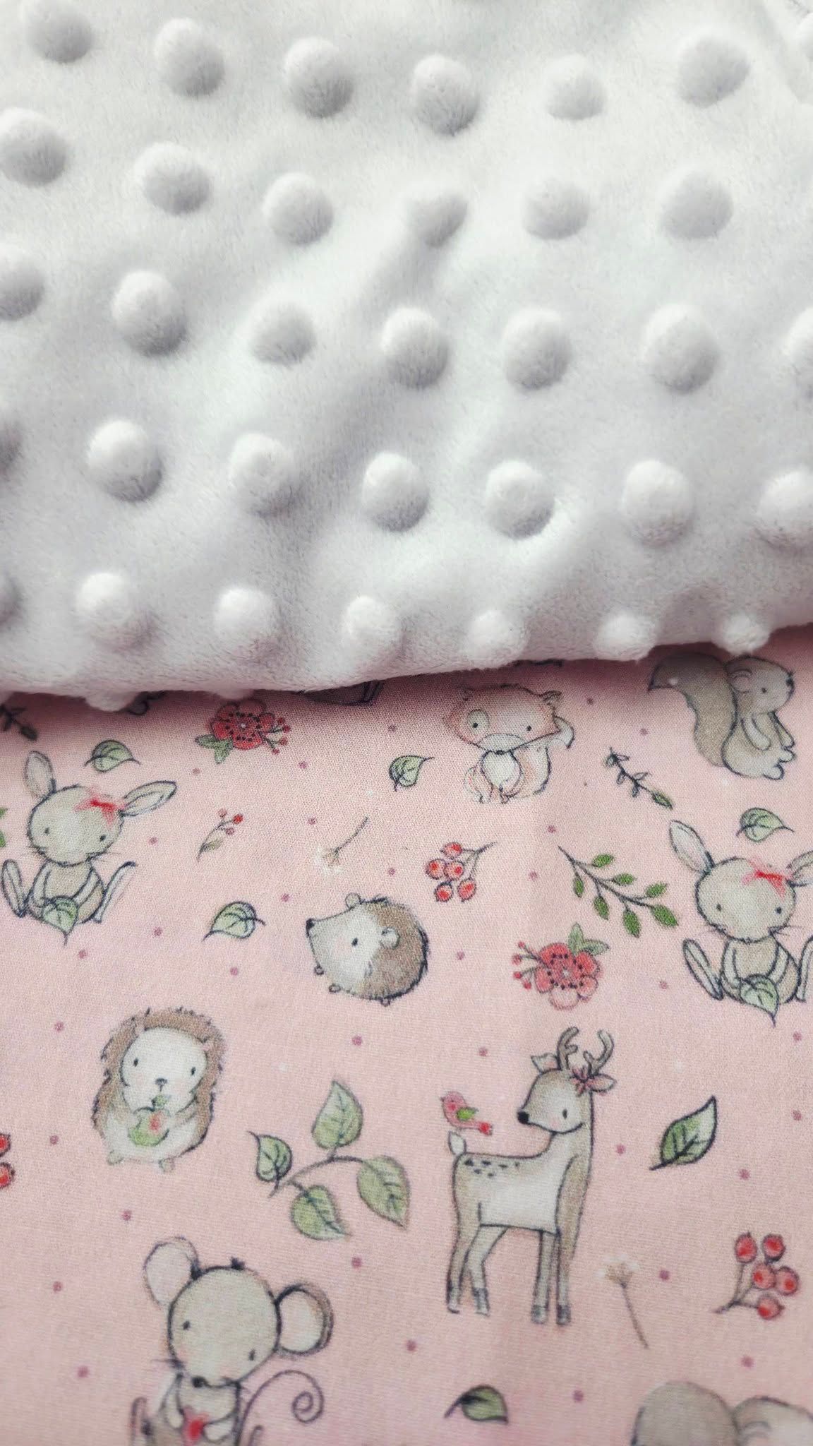 Soft white dimple minky fabric layered over pink woodland animals print baby blanket.