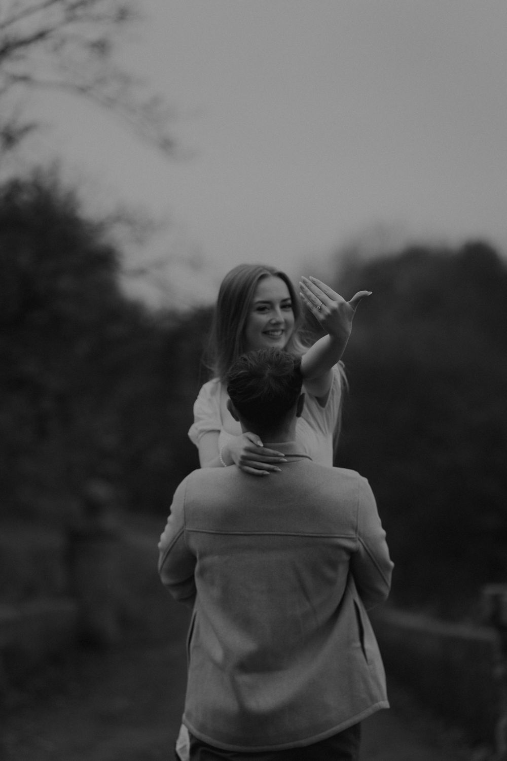 Man lifting smiling woman outdoors in black and white romantic couple photo session.
