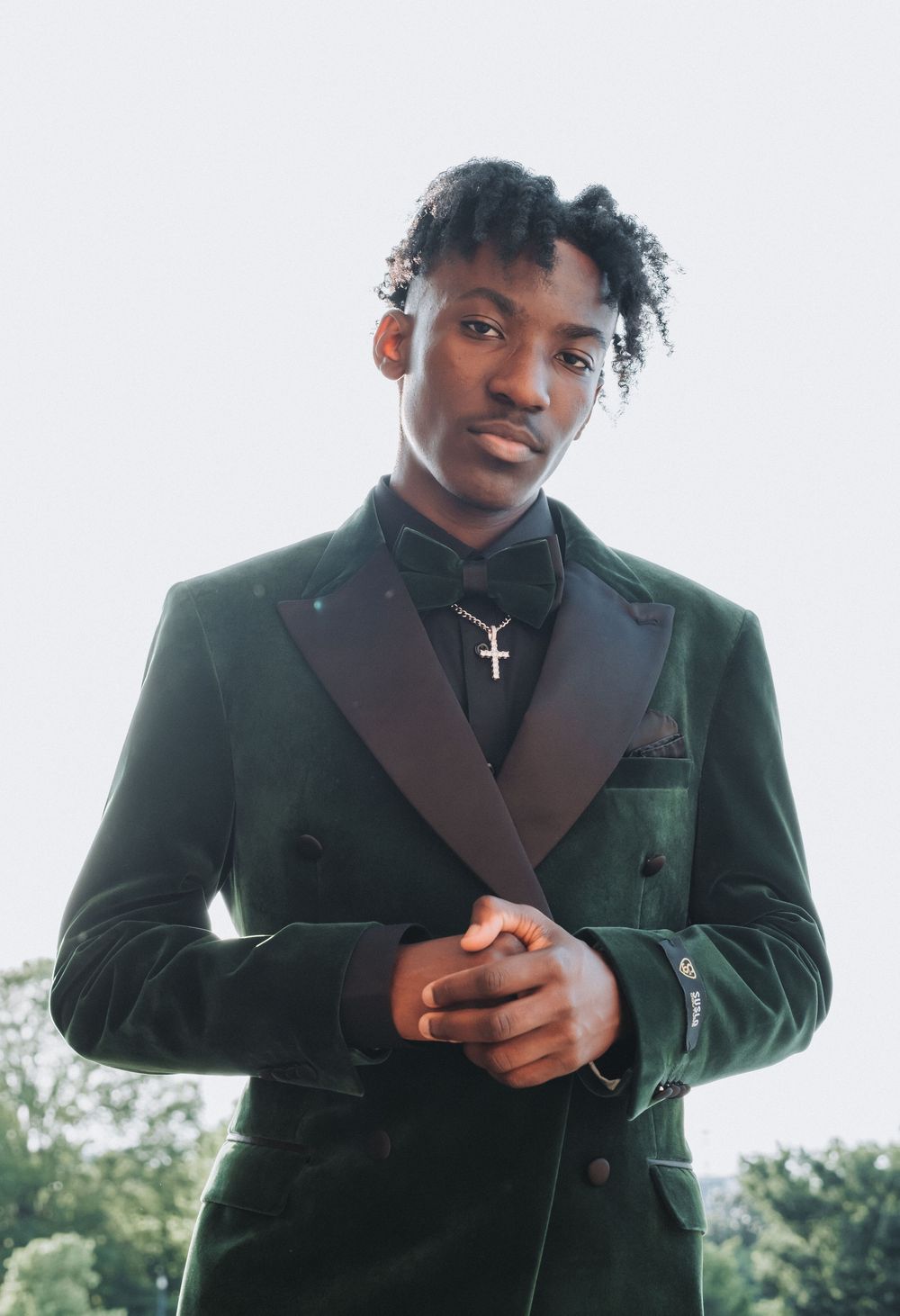 Formal portrait of person in emerald velvet double-breasted tuxedo with black lapels.