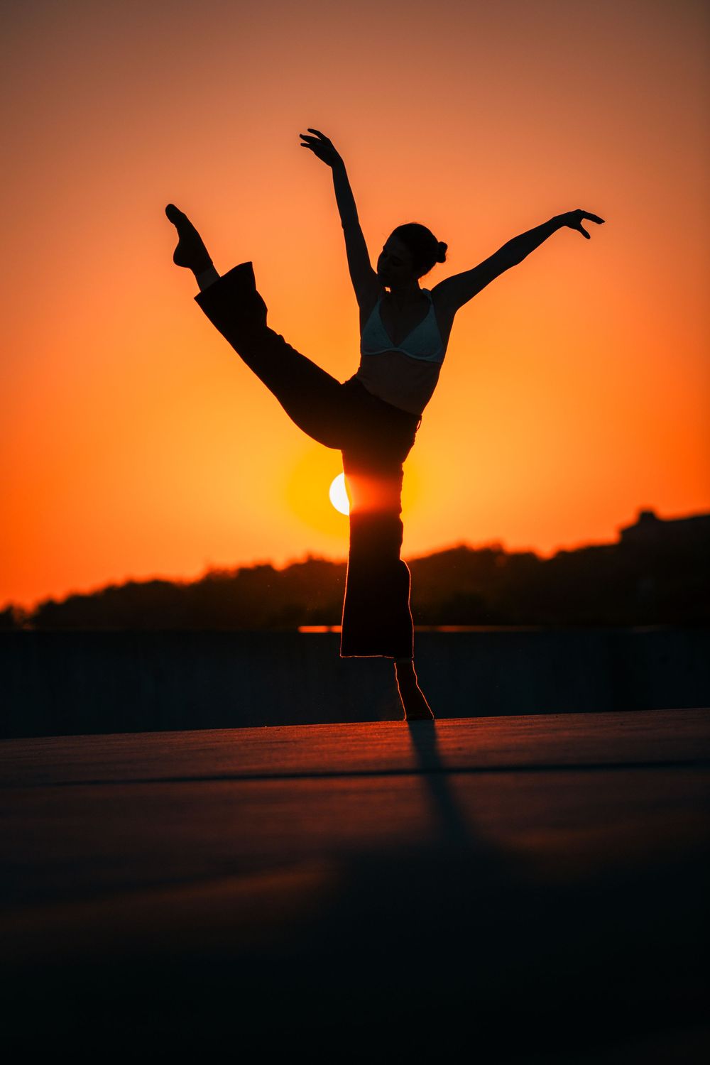 Dynamic silhouettes dancing and jumping against a dramatic orange sunset background.