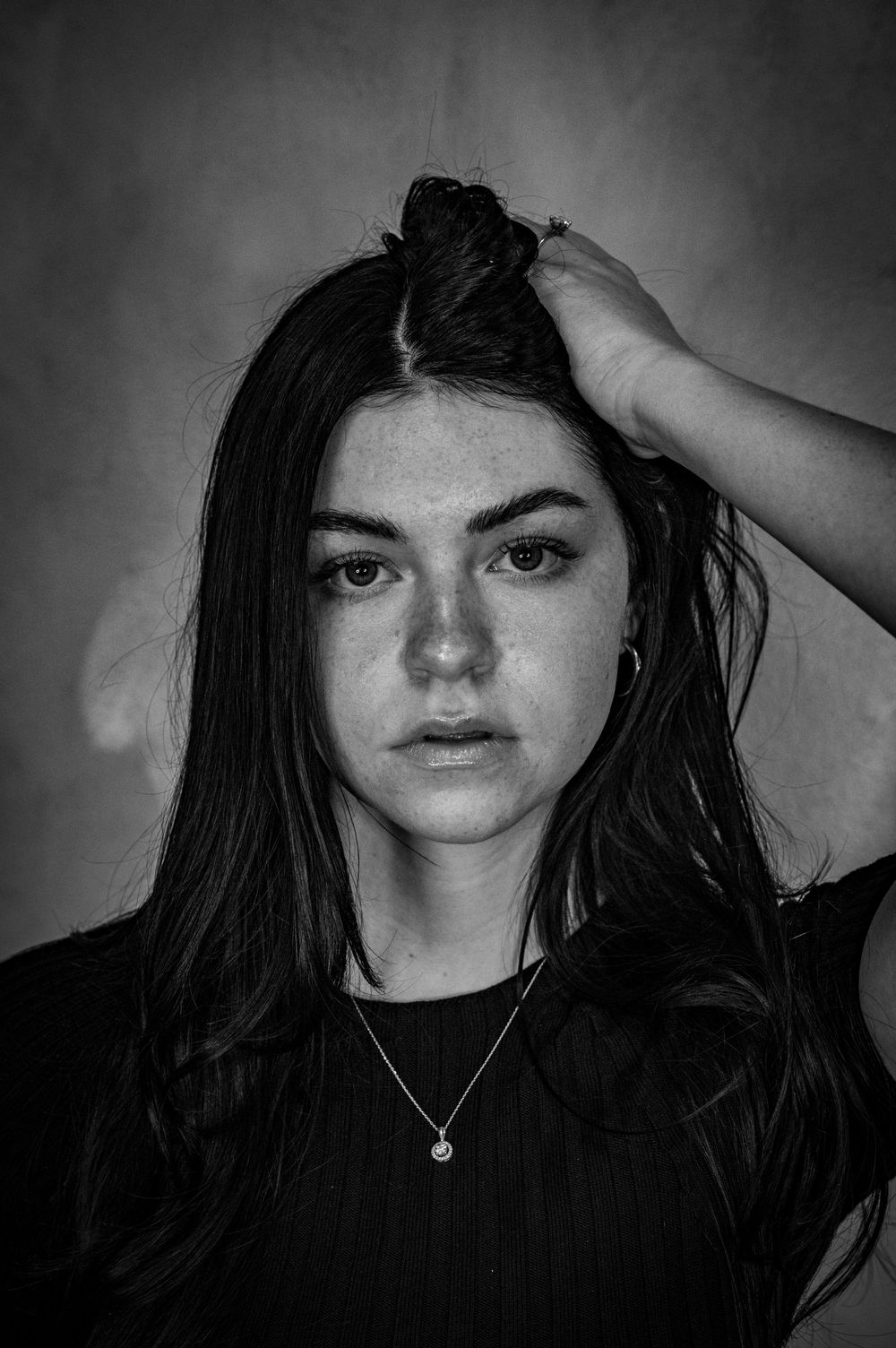 Black and white portrait of a young woman with long dark hair against neutral background.