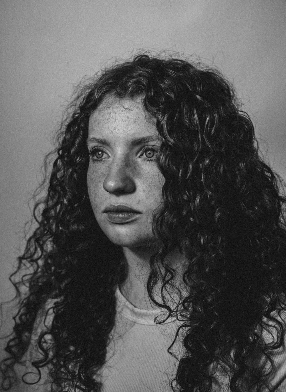 A black and white photo sequence showing dynamic movement of dark curly hair against a light background.