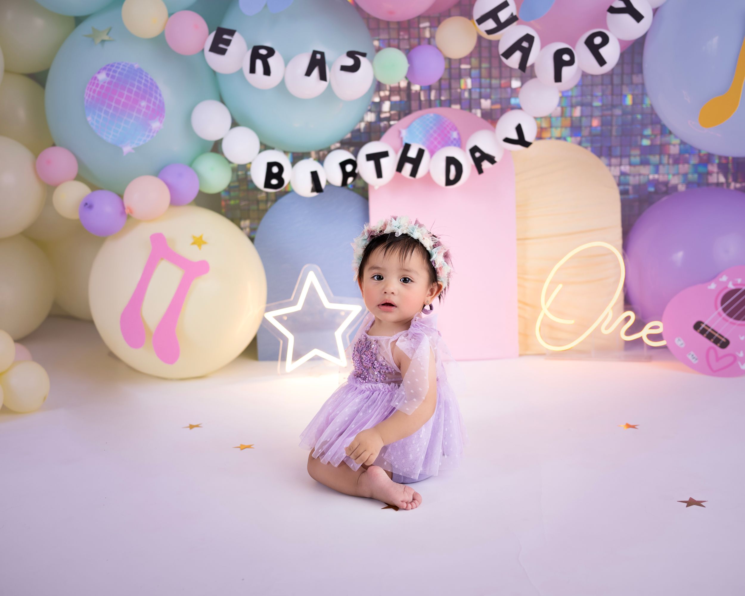 First birthday celebration setup with pastel balloons and musical decorations.
