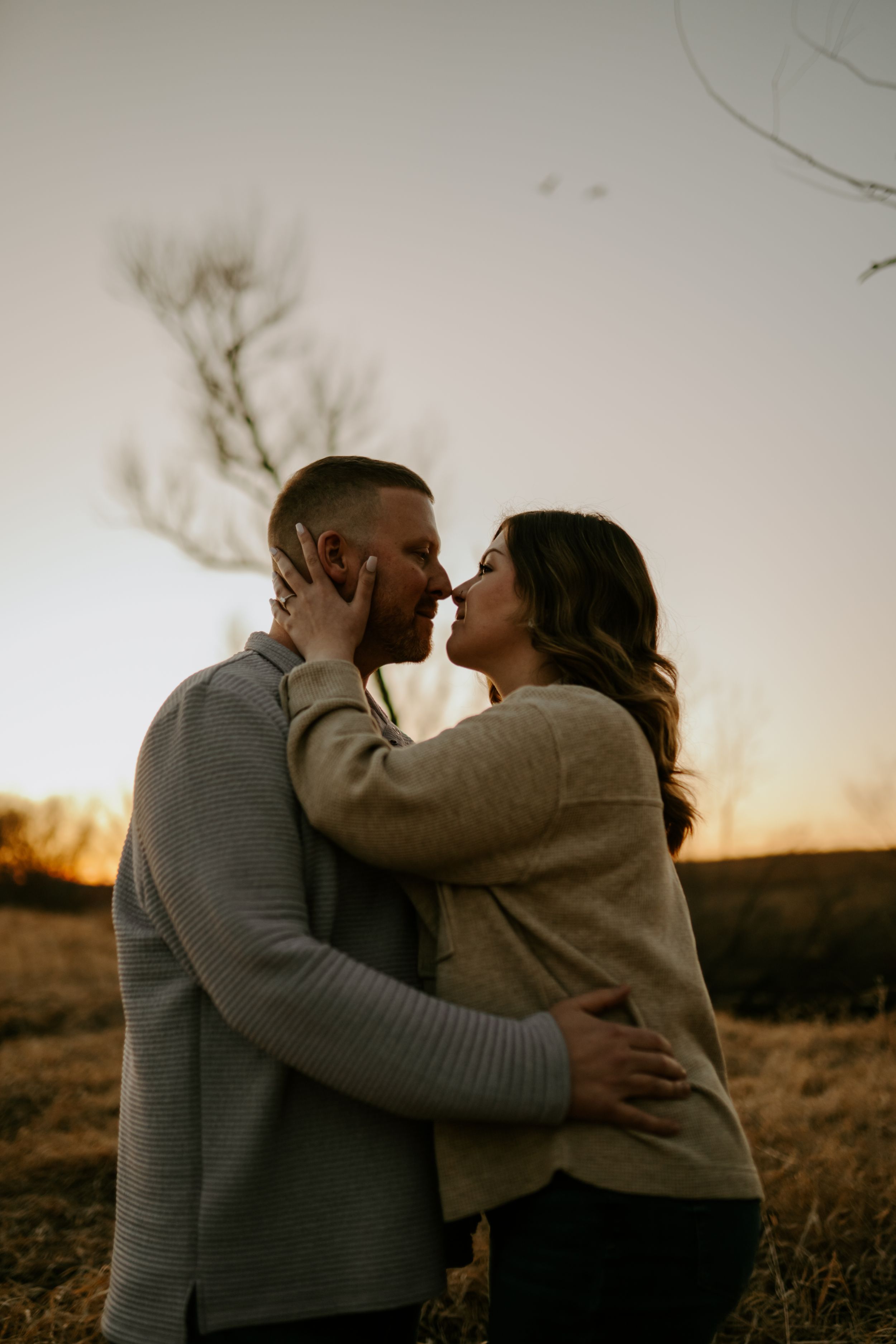 An intimate embrace between a couple during sunset in a natural outdoor setting.