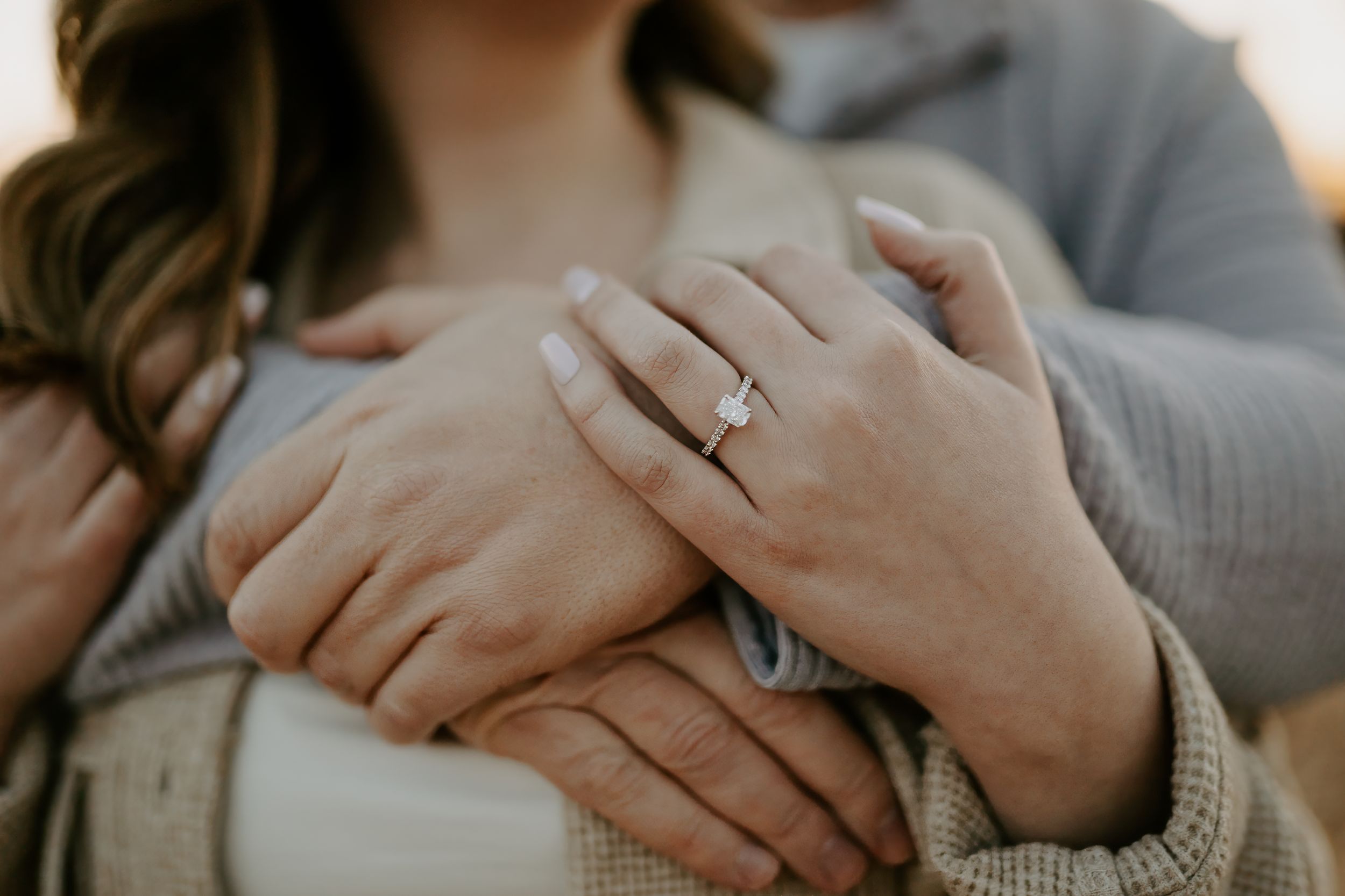 Intimate close-up photo showing hands and rings during an engagement session.