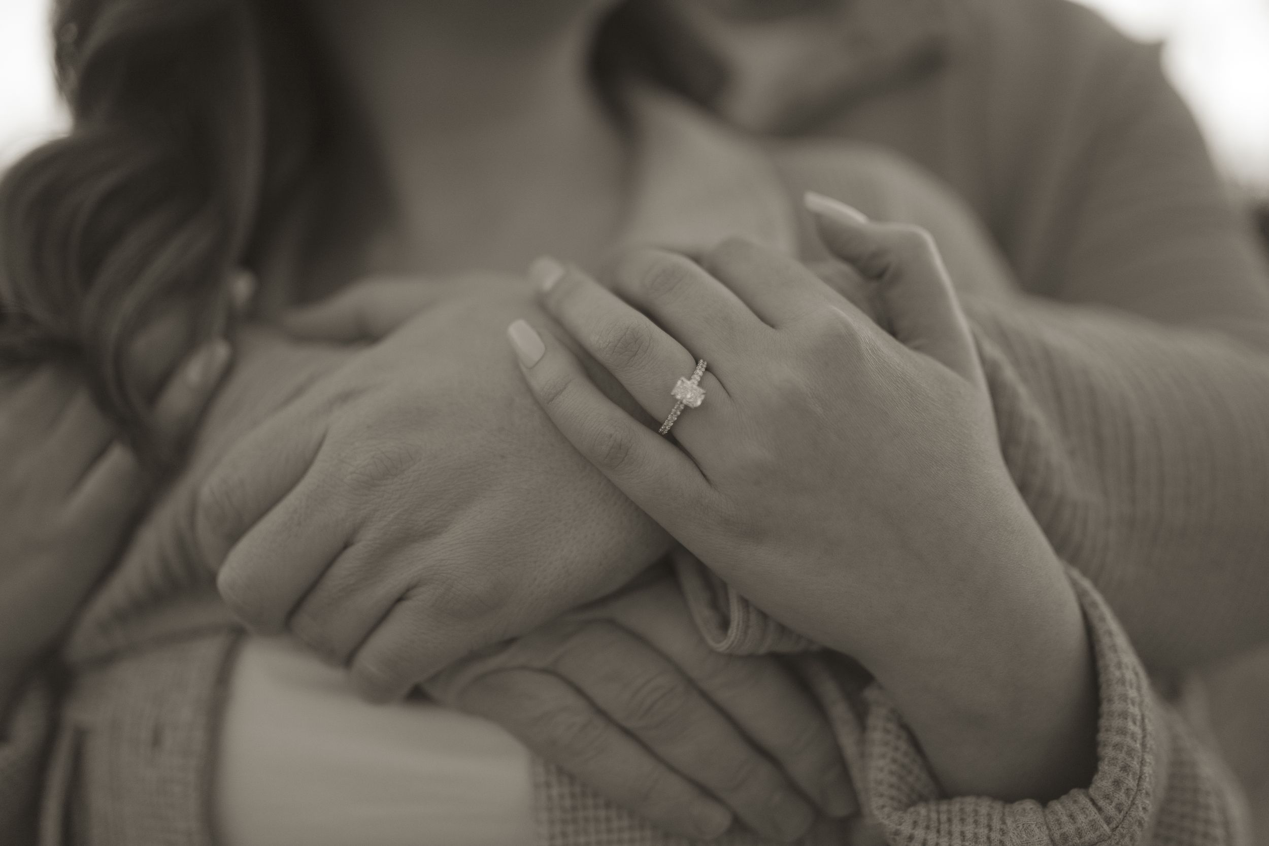 Detail shot of hands tenderly embracing during a romantic photo session.