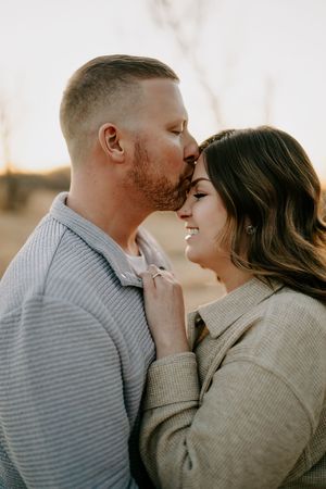 Romantic couple sharing an intimate moment during golden hour in a natural outdoor setting.