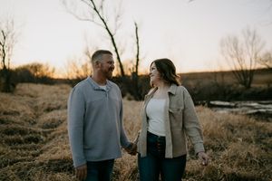 A couple shares loving glances while walking through a field at sunset.
