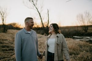 Couple embracing outdoors during sunset with warm lighting and natural scenery.