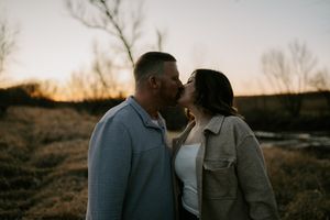 Silhouetted couple against sunset sky sharing tender moment by water.