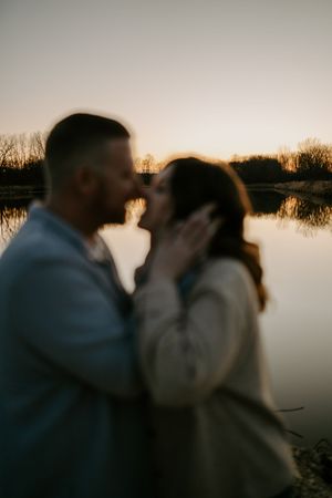 Intimate sunset portrait with couple in soft focus against water.