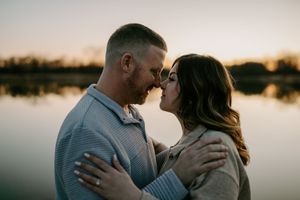 Couple sharing tender moment by lakeside during golden hour.