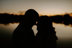 Dramatic silhouette of couple against sunset lake backdrop.