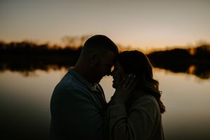 Romantic silhouettes against sunset lake with warm tones.