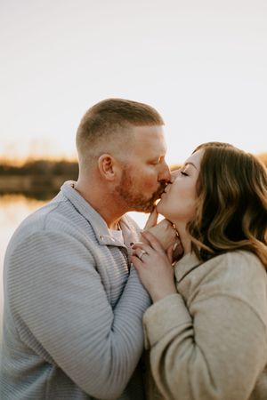Close-up of loving couple sharing gentle kisses near a lake.