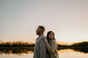 Couple in casual wear enjoying peaceful lakeside moment at dusk.