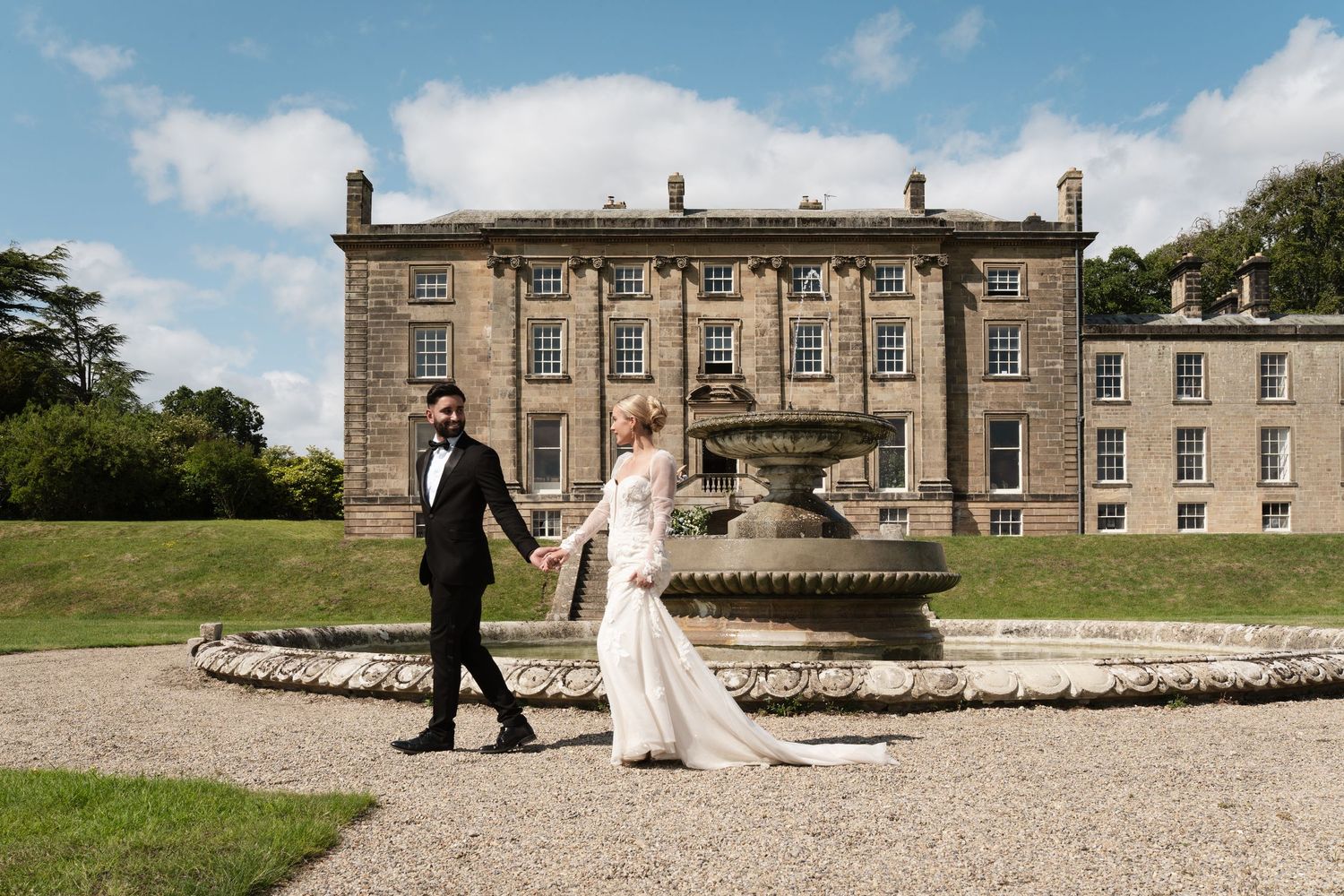 Wedding couple walking across the grounds of a grand historic mansion on their special day.