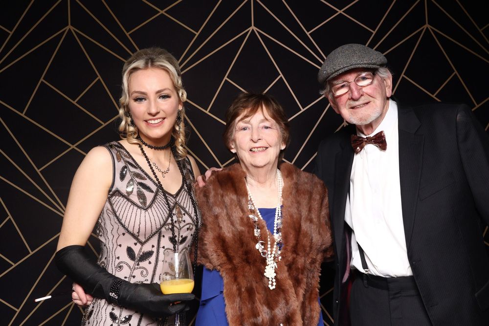 People socially gathered at an awards gala event wearing formal attire including fur coats and evening wear.