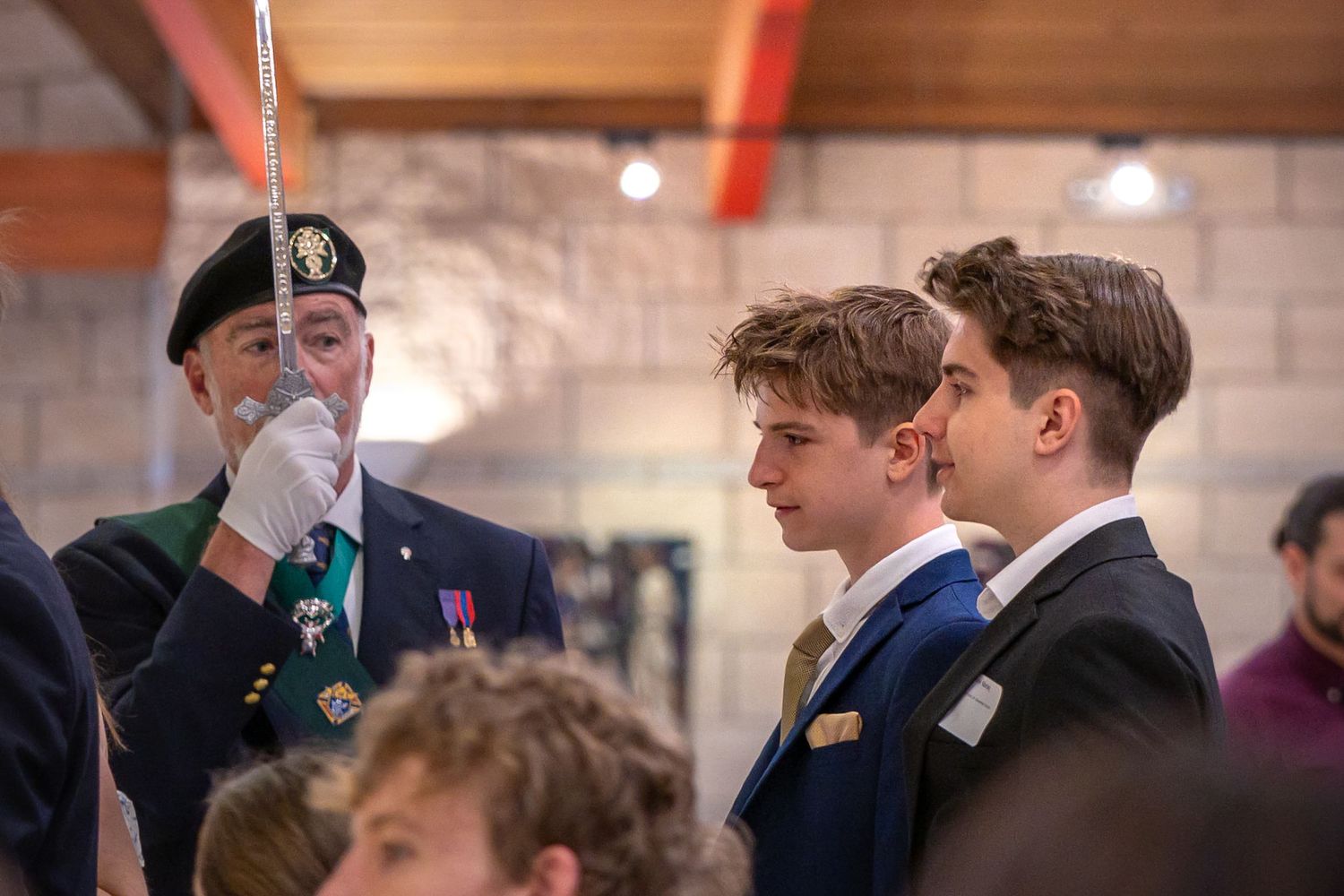 A young man is accompanied through St Mary of the Hills Catholic Church for his confirmation ceremony while a man stands guard with a sword
