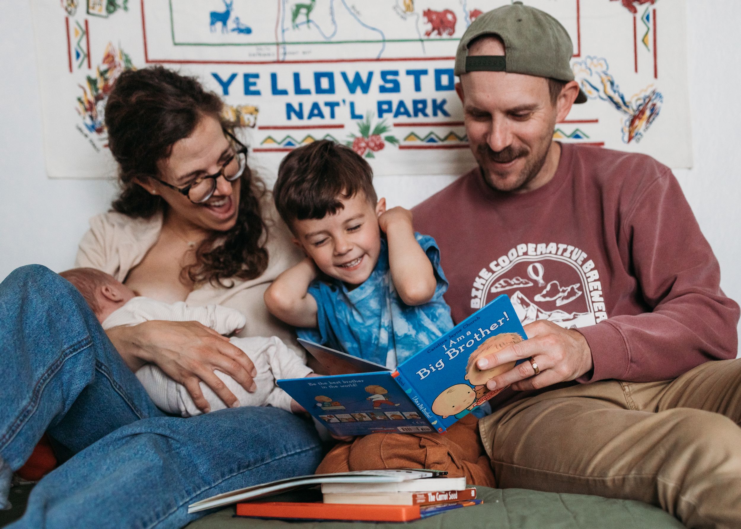 A family relaxes together on the couch reading books beneath a Yellowstone National Park sign.