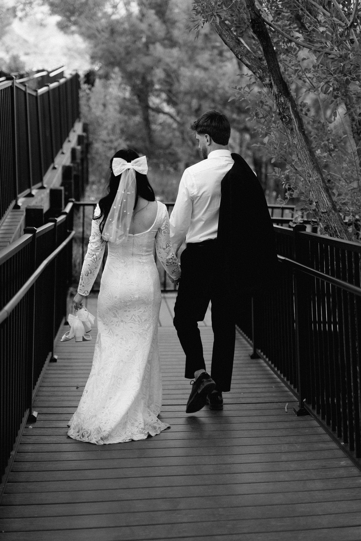 Black and white series captures romantic moments of a bride and groom strolling along a wooden bridge walkway at Red Rock in Las Vegas.