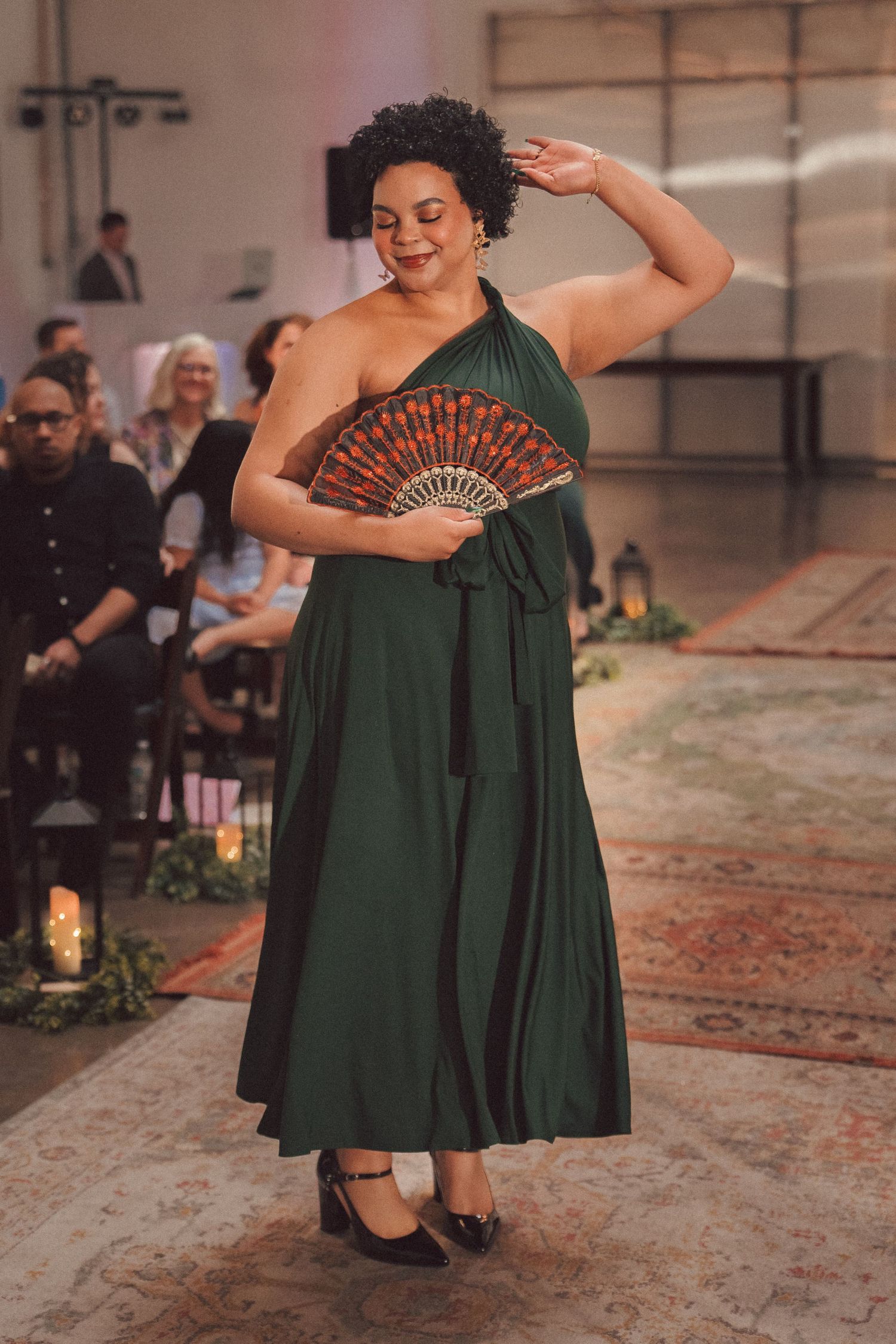 Bridesmaid in a flowing dark green dress walking down the aisle and pausing for a photo.